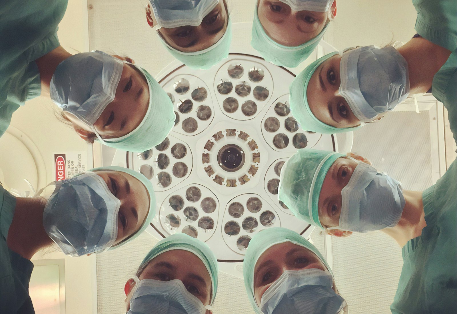 Surgical team looking down into camera around an operating light