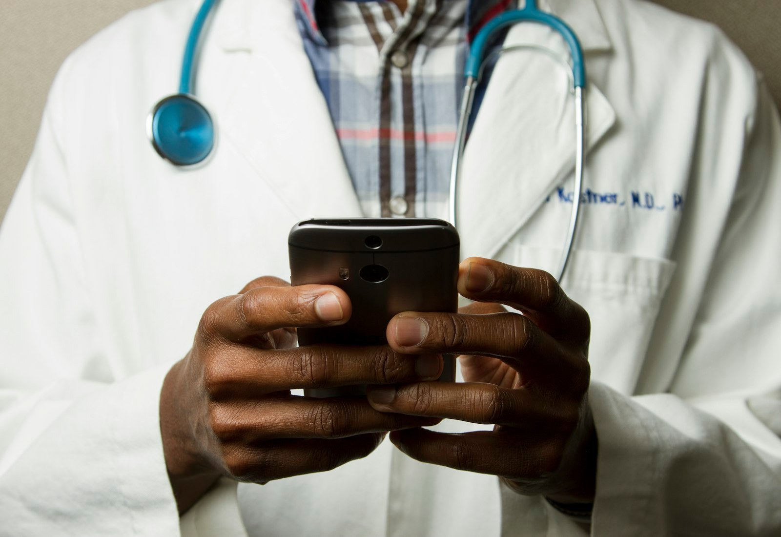 Clinician in a white coat holding a phone in both hands